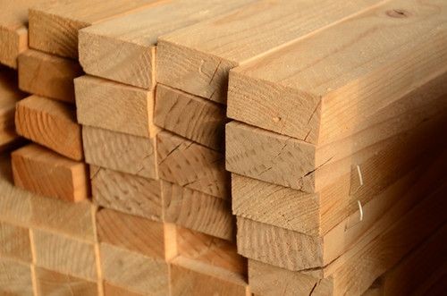 Stack of light brown wooden planks arranged neatly, showcasing natural grain and texture.